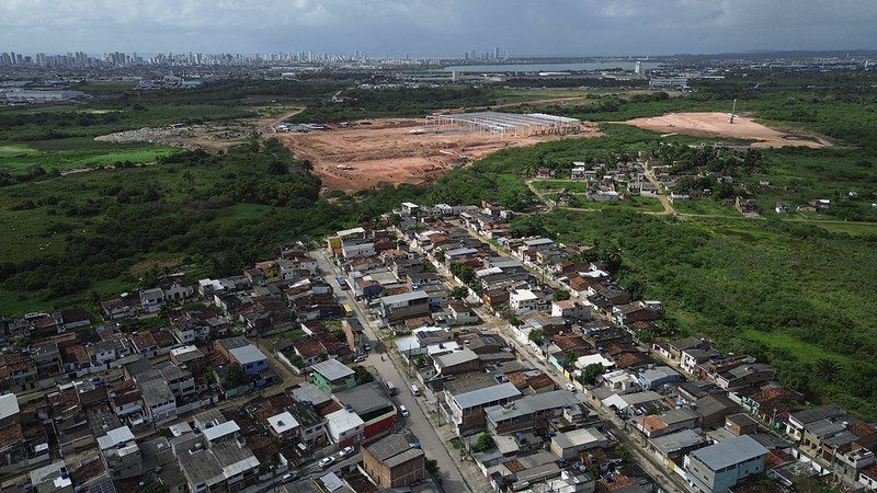 imagem sugerida: vista aerea de terreno urbano com corrego na divisa e construcao ao lado