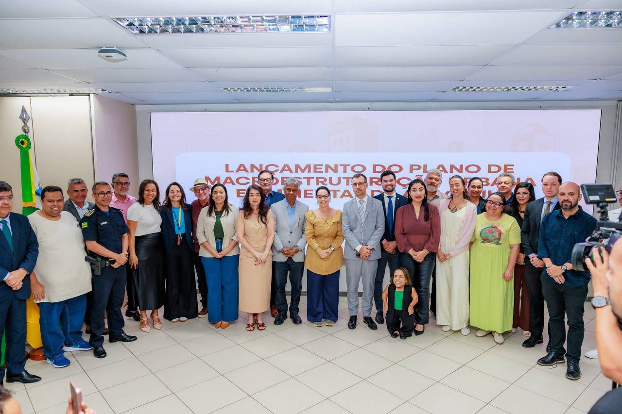 imagem sugerida: foto do auditorio da prefeitura durante o evento de lancamento, com o colaborador do escritorio entre os convidados