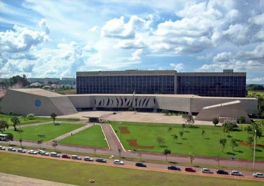 imagem sugerida: fachada do edificio-sede do stj em brasilia, com as colunas e o espelho d'agua, em dia claro, foto institucional em tons ne